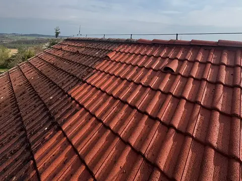 Strecha rodinného domu počas čistenia – vyčistená a&nbsp;znečistená časť krytiny.